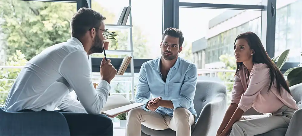 young married couple talking while sitting on the therapy session with psychologist