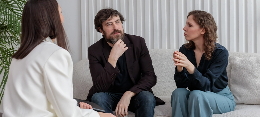 female psychologist sits and listens to the family couple during therapy session