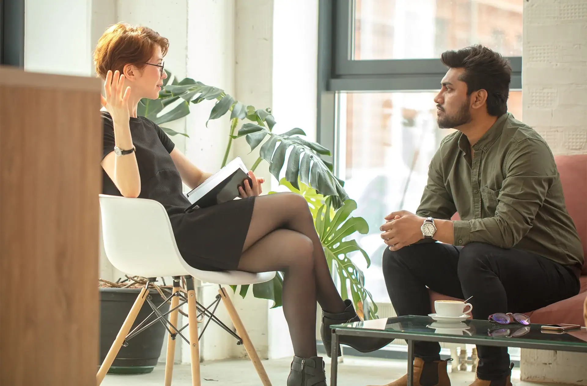 young female psychologist working with indian man in modern office