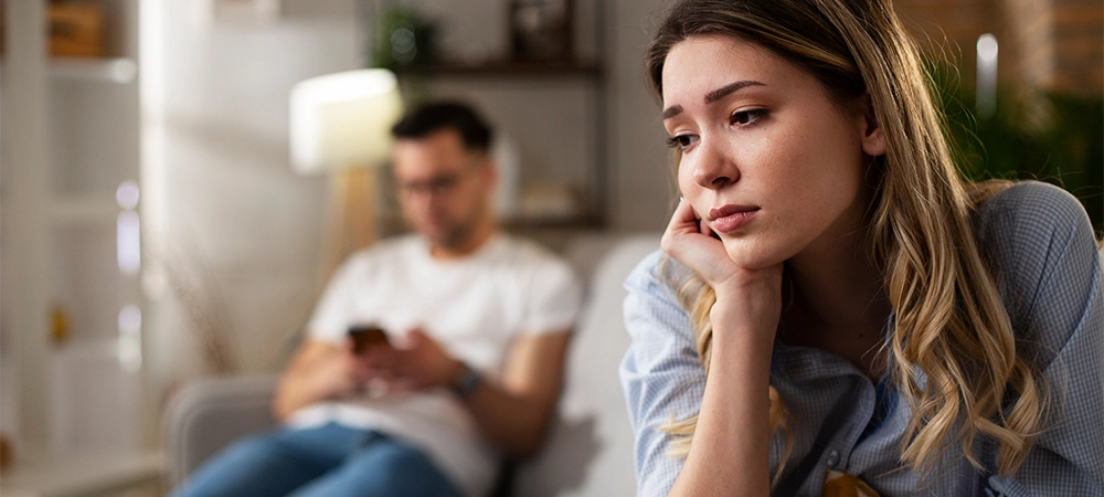 couple at home after having a fight, sad depressed woman sitting on sofa