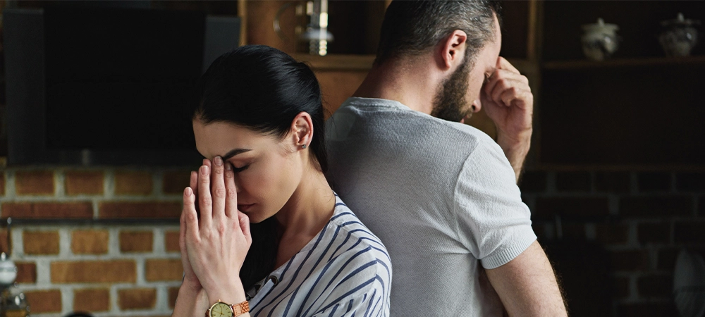 young depressed couple standing back to back after argument