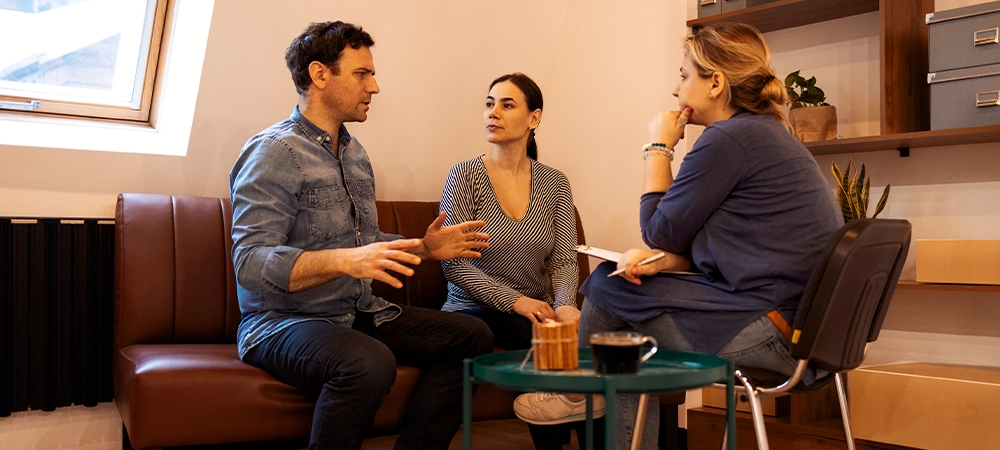 Couple therapy. Nice serious couple visiting a psychologist and having a psychological session while dealing with problems in relationships together